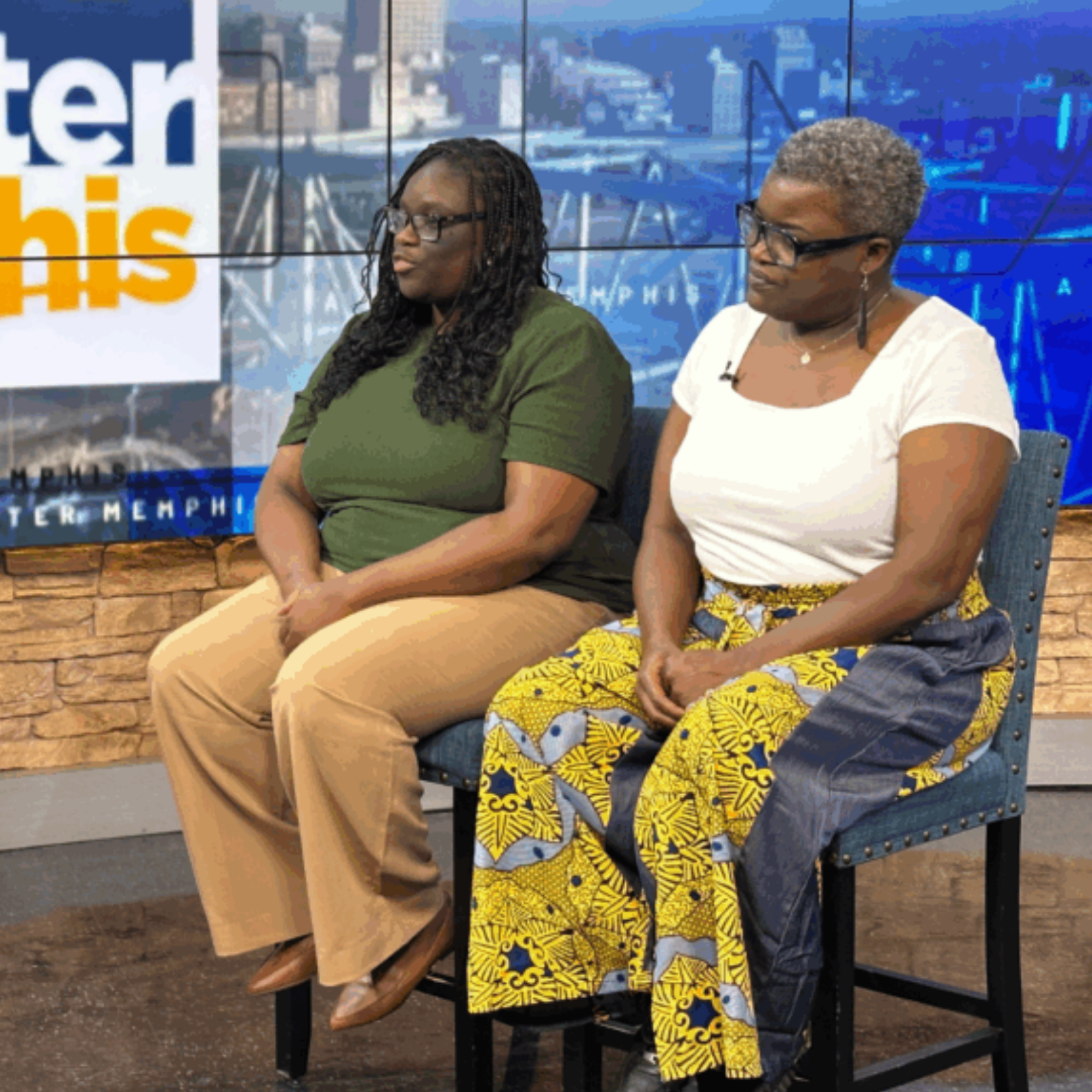 Two women sit side by side on chairs in a studio setting. A Memphis sign appears in the background as they discuss the Give 8/28 Campaign, which supports Black-Led Nonprofits raising $3 Million for impactful community change.
