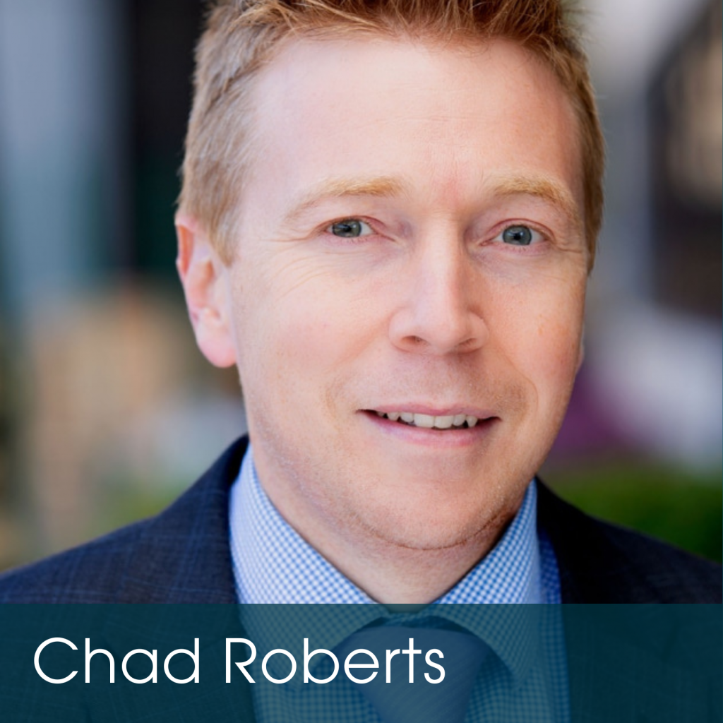 A man with short light brown hair, wearing a blue suit and tie, smiles at the camera. The background is blurred, highlighting Chad Roberts’ name at the bottom and reflecting the confidence that comes with estate planning benefits.