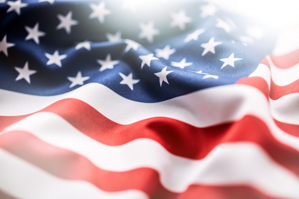Close-up of the United States flag showing red and white stripes and white stars on a blue field, with the fabric appearing soft and slightly waved.